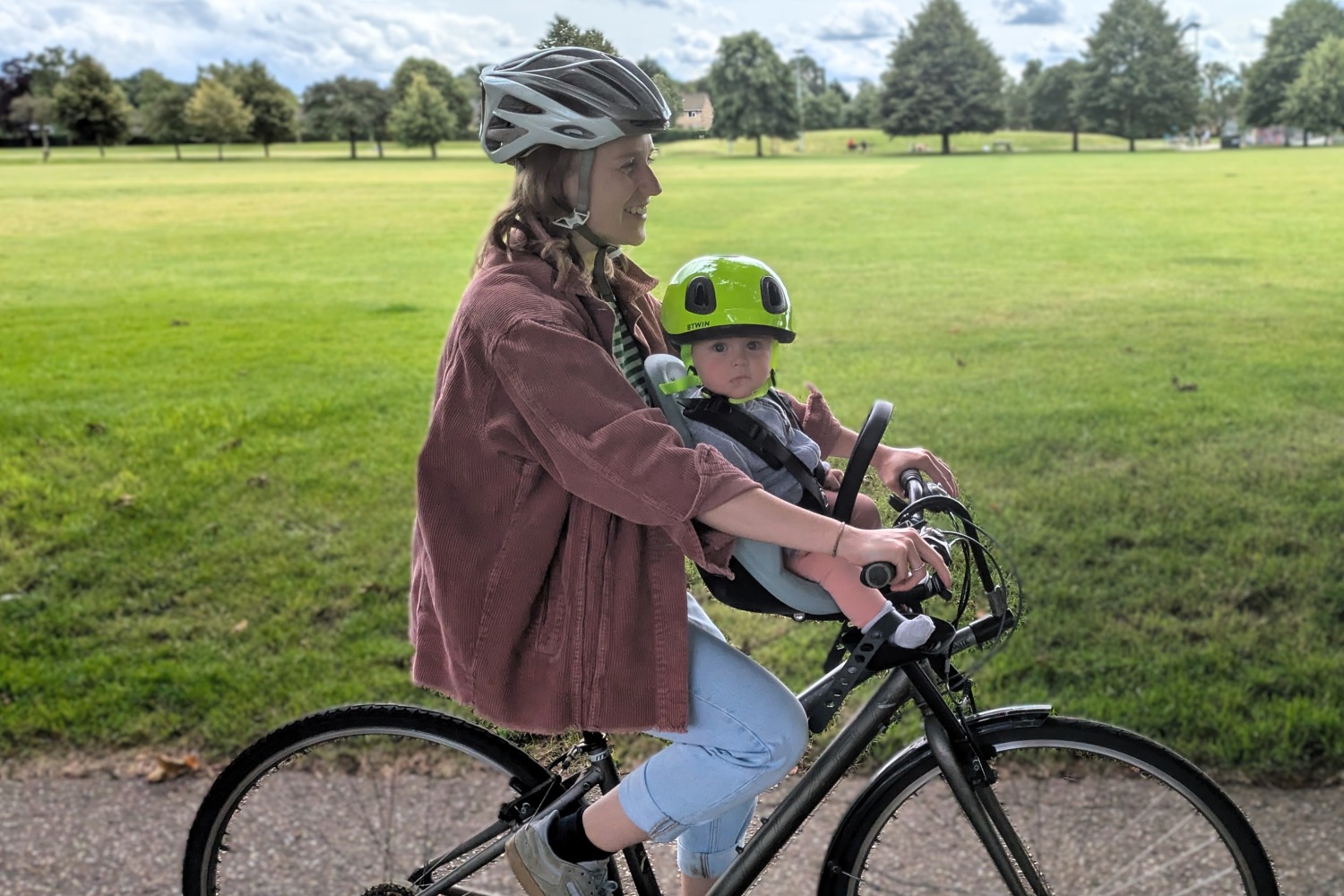 Cycling while breastfeeding: a woman seen from the side, cycling with a baby in a front-mounted child seat