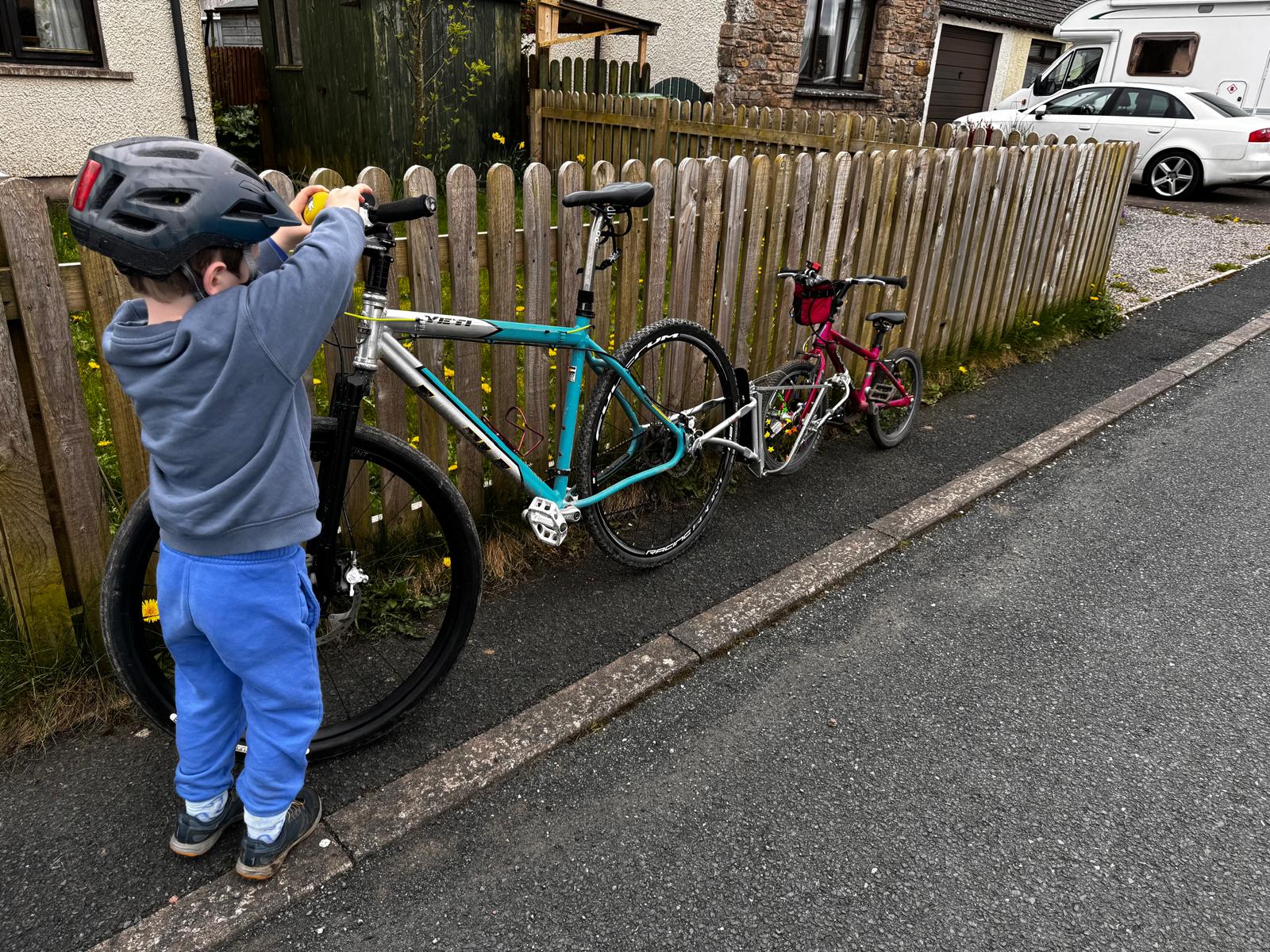 little boy playing whith his dads bike that has a pink bike attatched with a FollowMe Tandem