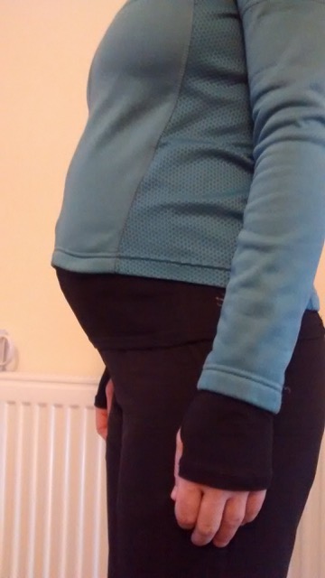 Cycling during pregnancy: A side view of Saskia from the chest down, showing her cycling kit over her pregnant belly