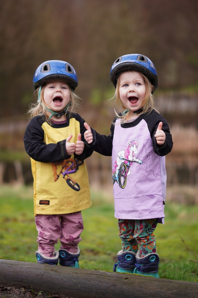Kids Ride Shotgun seat review, two very smiley twin girls in blue helmets
