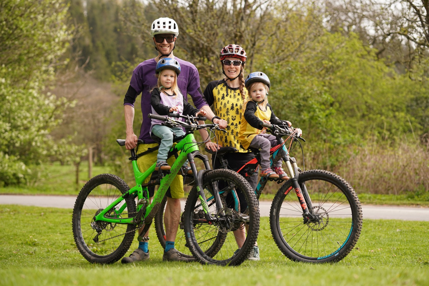 Kids Ride Shotgun seat review, a family photo of two parents on their mountain bikes with their twin daughters on shotgun seats