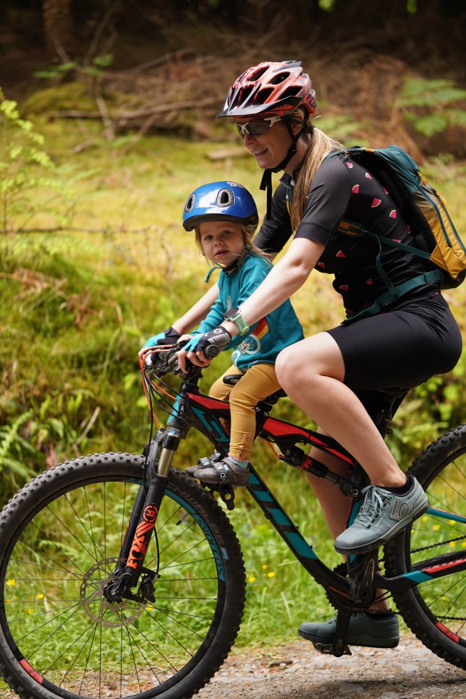 Kids Ride Shotgun seat review, side on photo of a mum and daughter riding on an off road trail