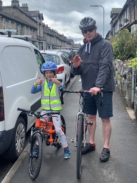 a photo of the orange child's mountain bike being ridden by a girl with her dad