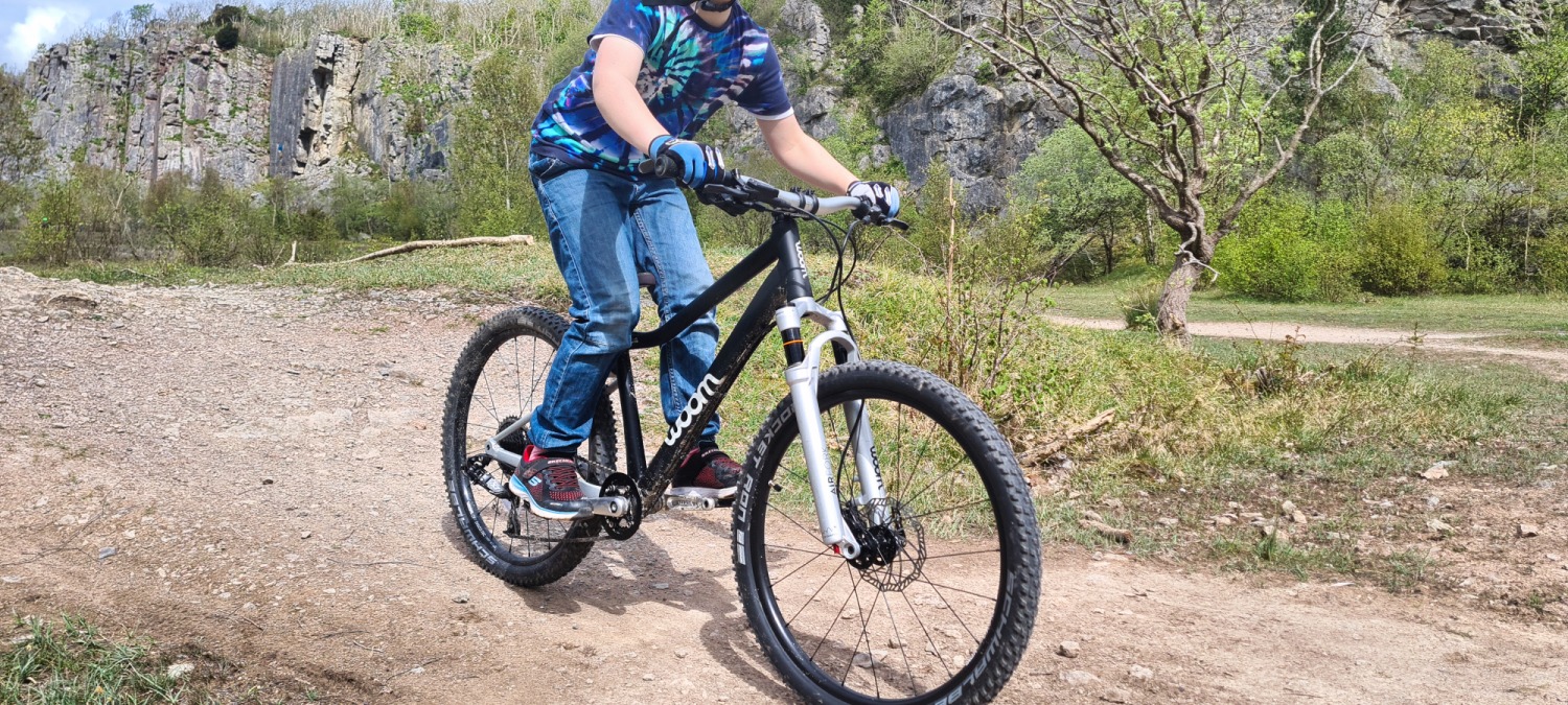 woom OFF AIR 5 review: boy riding the woom OFF AIR 5 mountain bike on a dirt trail