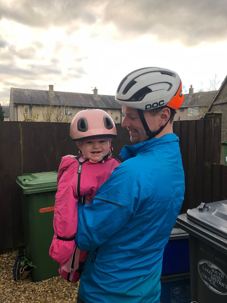 baby with pink helmet on being held by her dad