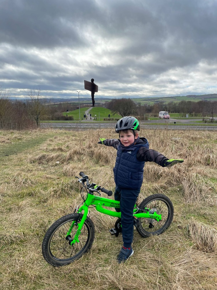 boy in a TI-GO BMX Hoodie standing with his green bike in front of the angel of the north