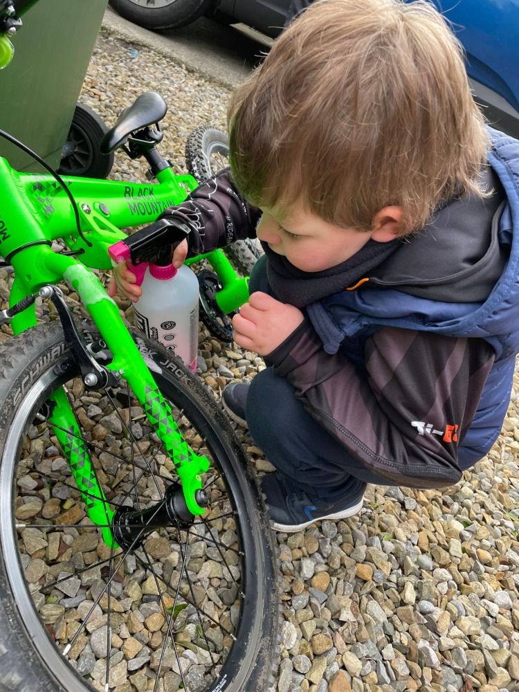 boy in a TI-GO BMX Hoodie cleaning his green bike