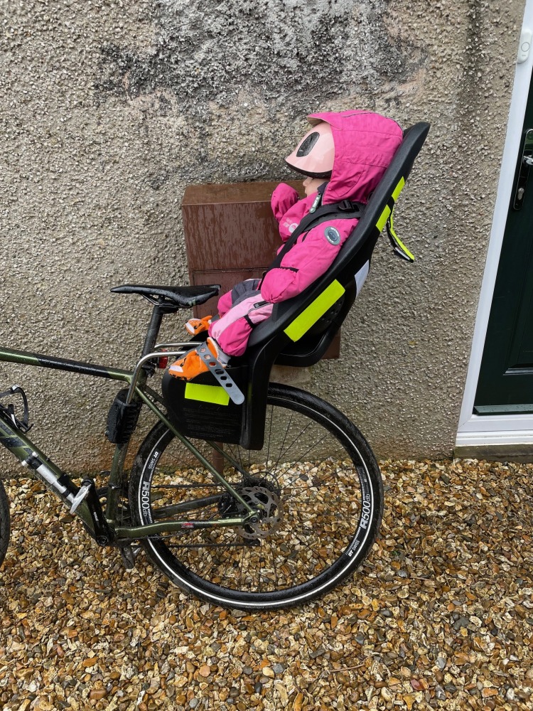 girl in a pink onesie loaded up on her thule yepp 2 maxi rear seat for a bike ride.