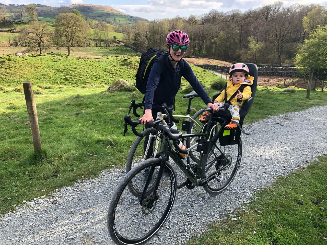 Thule Yepp 2 Maxi rear seat in use, a little girl in a yellow jacket is on the back of her mums bike on a bike ride in the lake district