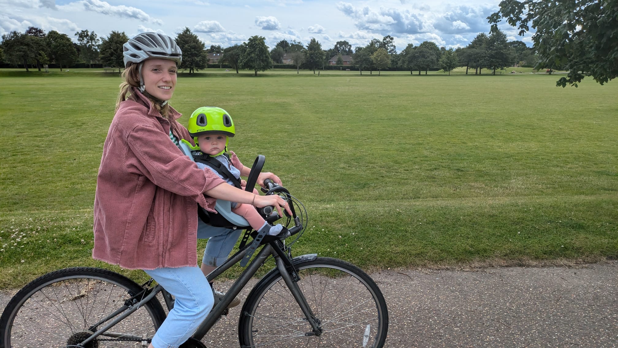 Thule Yepp 2 mini review: a woman seen from the side, cycling with a baby in a front-mounted child seat