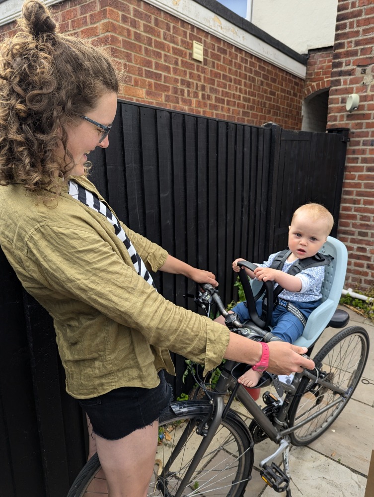 Thule Yepp 2 mini review:a little girl in a yellow helmet sat in a Thule Yepp 2 Mini front bike seat with a woman holiding the bike