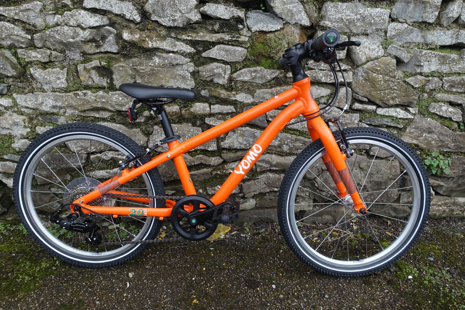 Best kids' bikes: A YOMO bike pictured from the side, leaning against a brick wall