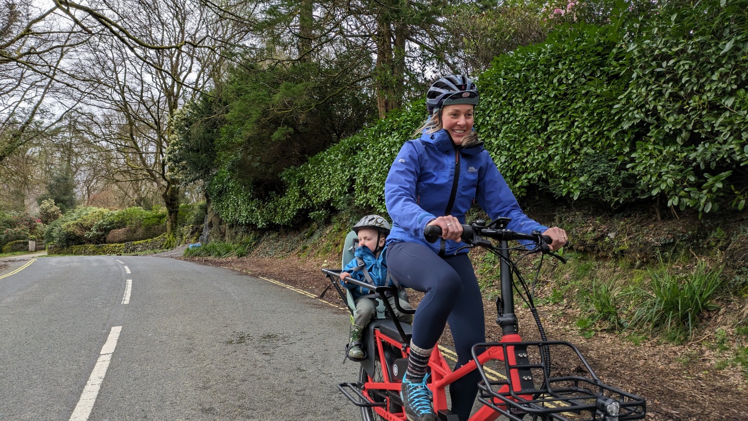 mum riding the estarli ecargo longtail bike with her son in a blue jacket on the back