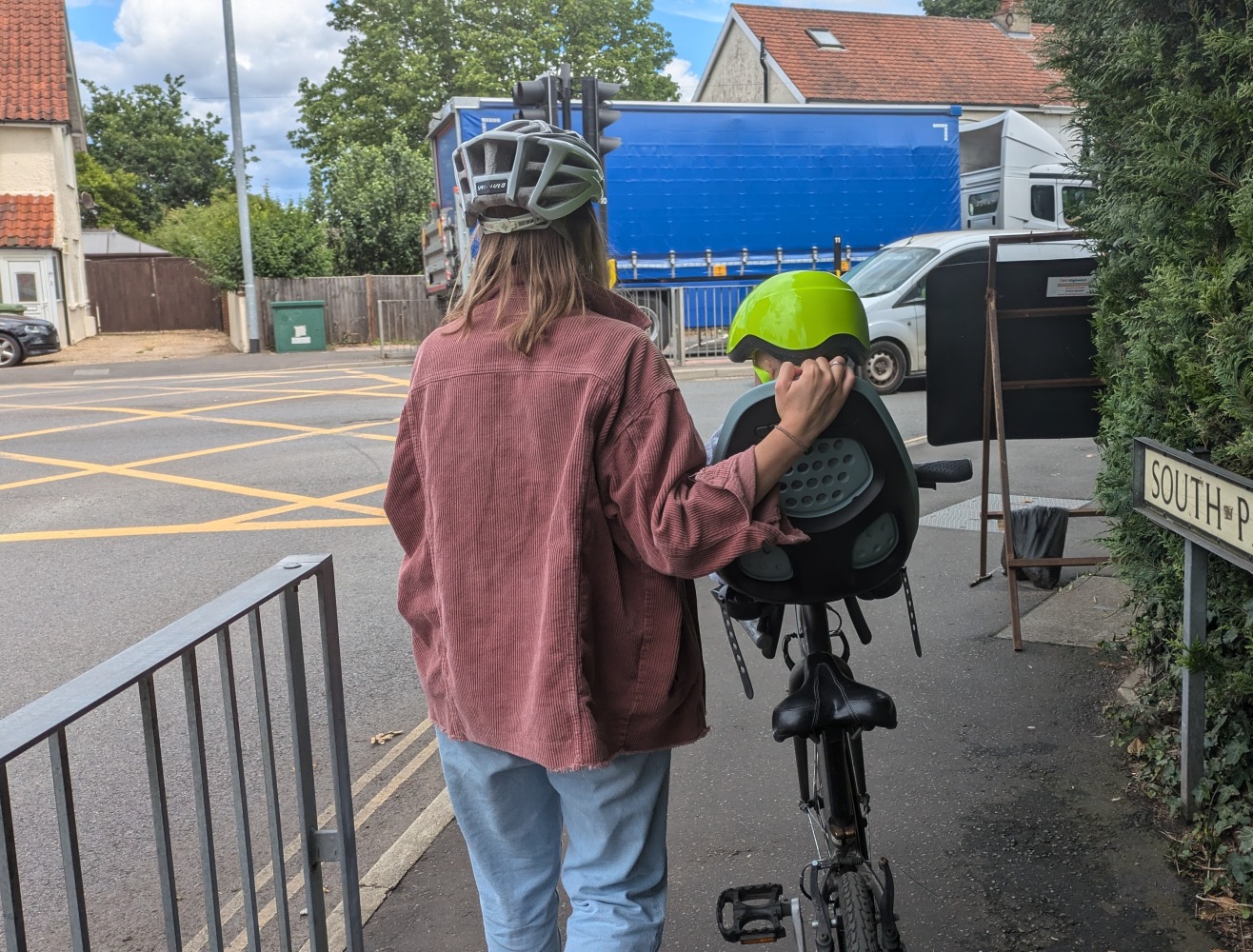 Thule Yepp 2 mini review: a woman pushing her bike with a baby in the front seat