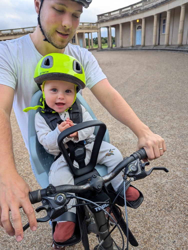 Thule Yepp 2 mini review:a little girl in a yellow helmet sat in a Thule Yepp 2 Mini front bike seat with her dad riding the bike