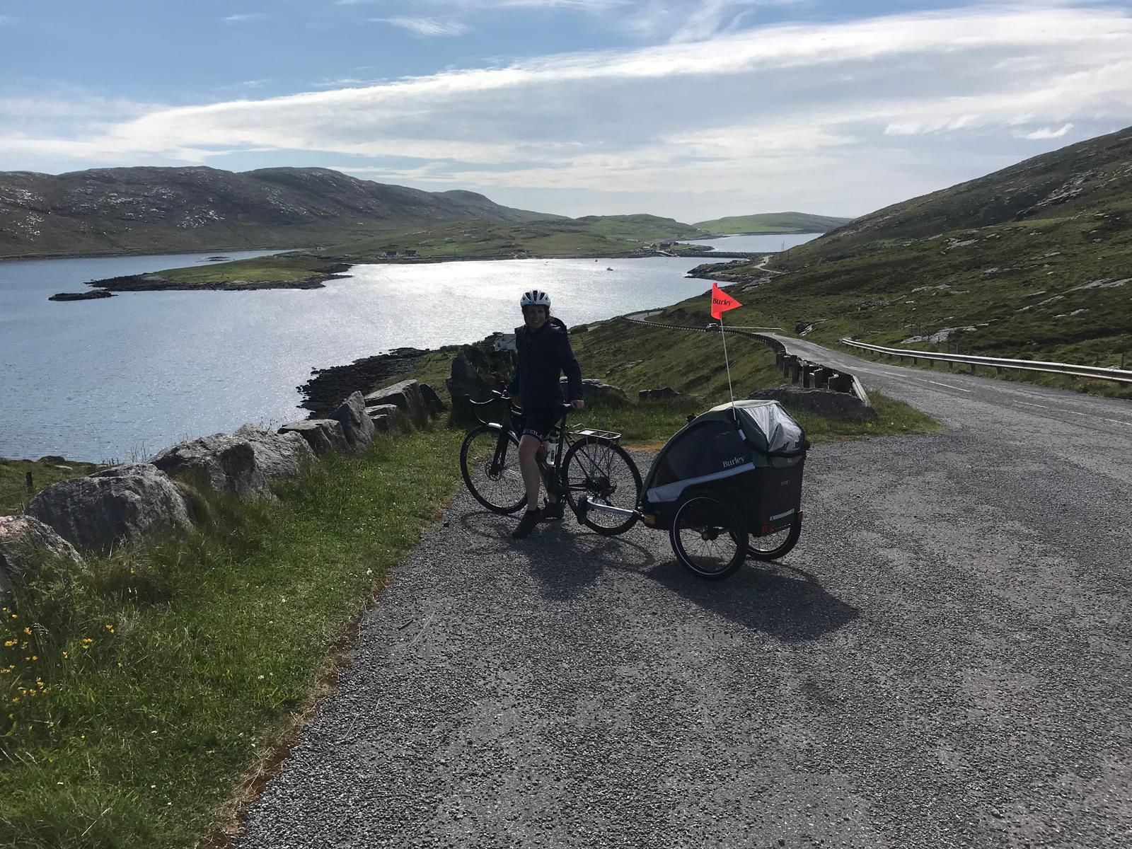 dad riding with the Burley D'Lite X child trailer in scotland with the sea behind him