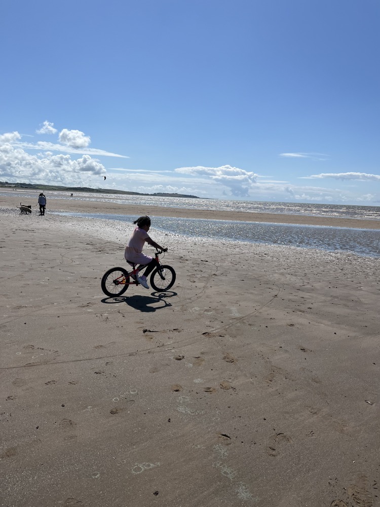 a black girl riding her kidvelo rookie 18 on the beach on a sunny day