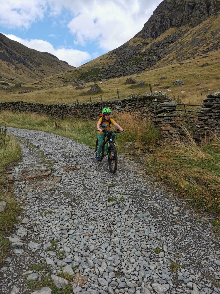 Cube acid 240 MTB review- a girl in a yellow t-shirt is riding the cube acid mtb on a bumpy mountain bike trail on a misty day in the mountains