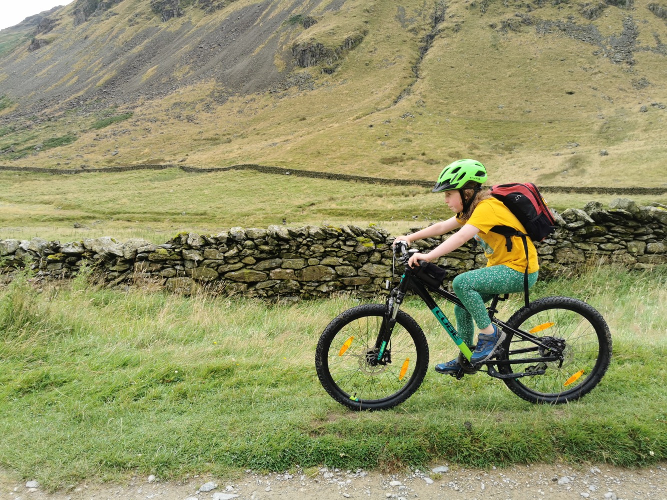 Cube acid 240 MTB review- a girl in a yellow t-shirt is riding the cube acid mtb on a bumpy mountain bike trail on a misty day in the mountains