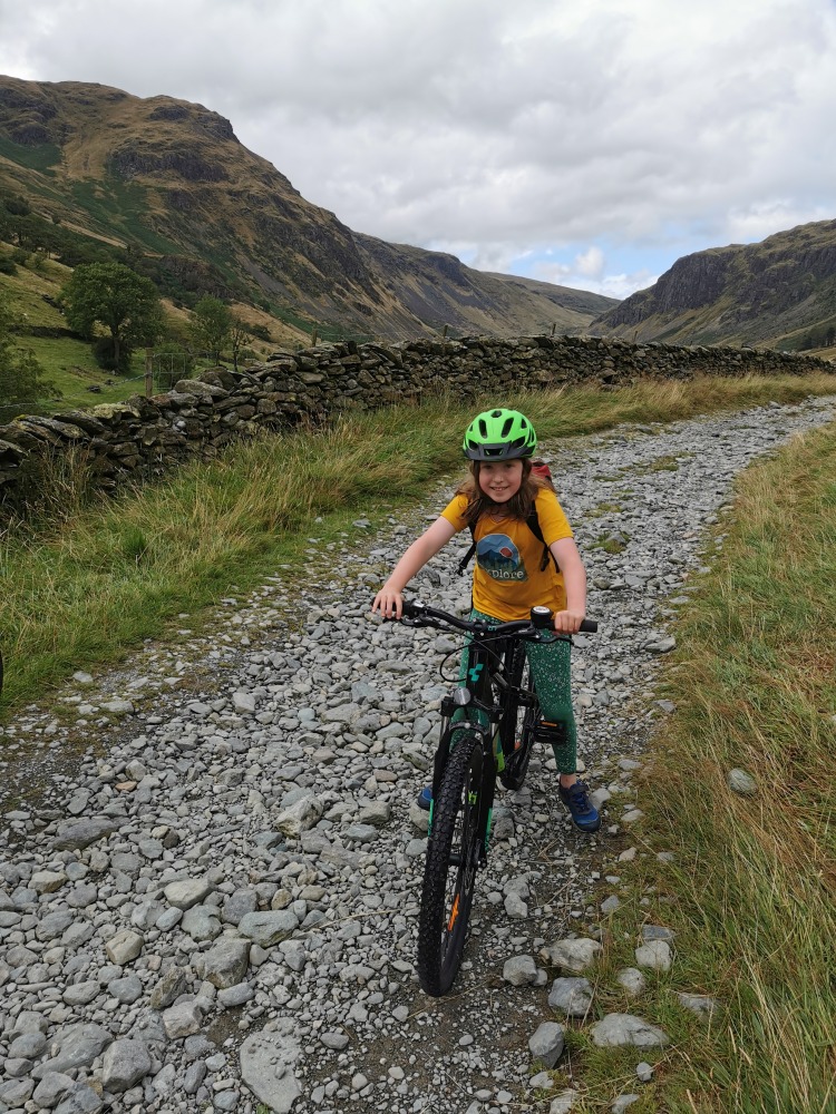 Cube acid 240 MTB review- a girl in a yellow t-shirt is riding the cube acid mtb on a bumpy mountain bike trail on a misty day in the mountains