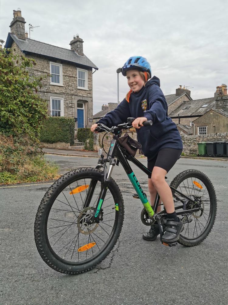 Cube acid 240 MTB review- a girl in a navy hoodie is riding the cube acid mtb on a road