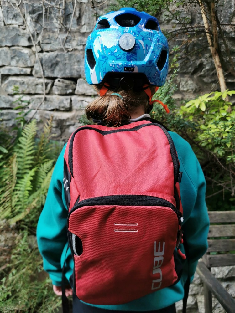 cube rookie red backpack being worn by a girl with a blue helmet and school jumper