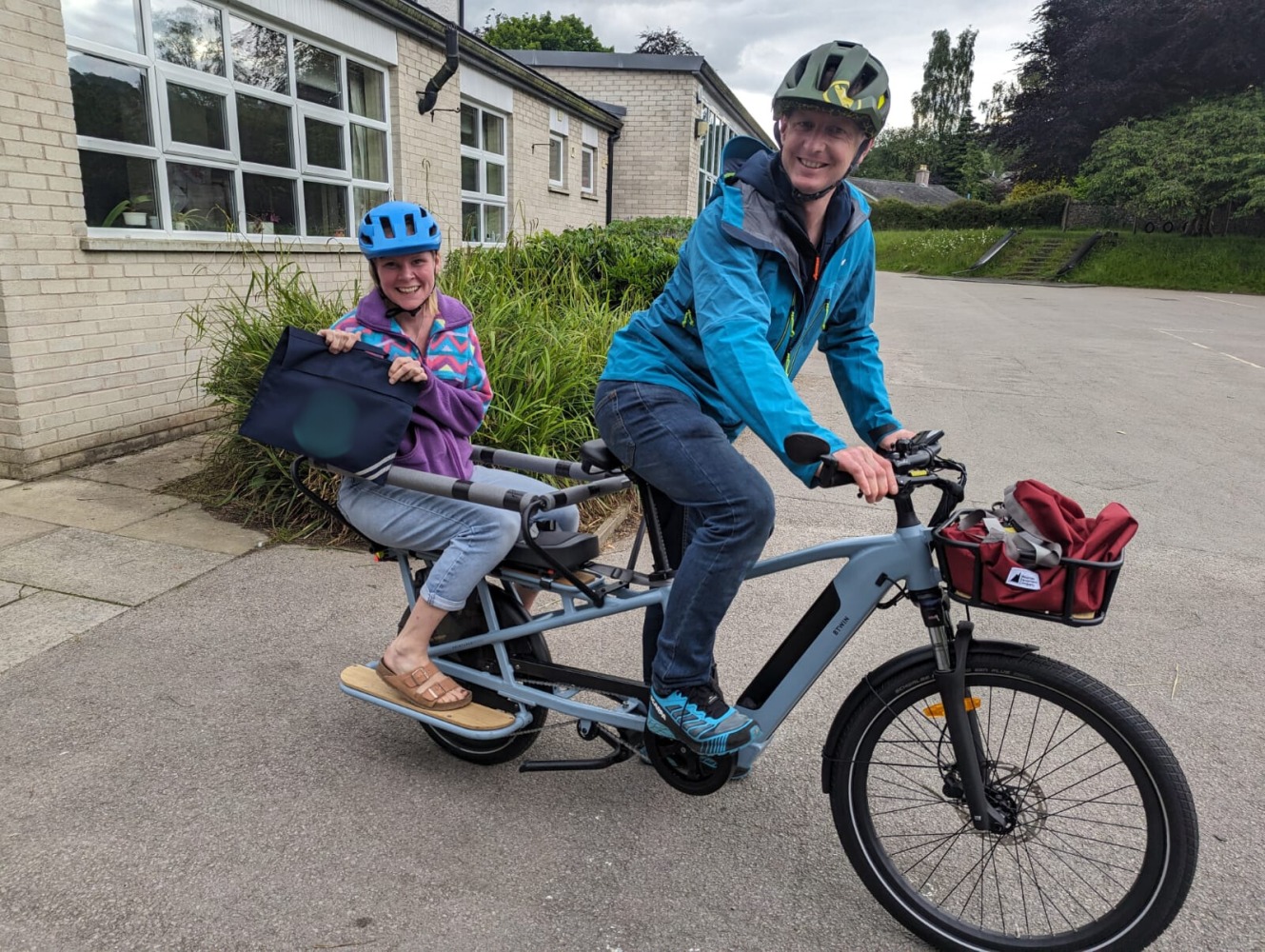 a mum and dad riding home from the school drop off on a longtail cargo bike