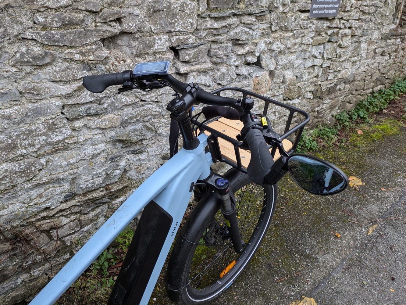 photo of the front rack of a light blue Decathlon longtail cargo bike with a rear rain cover on leant against a brick wall