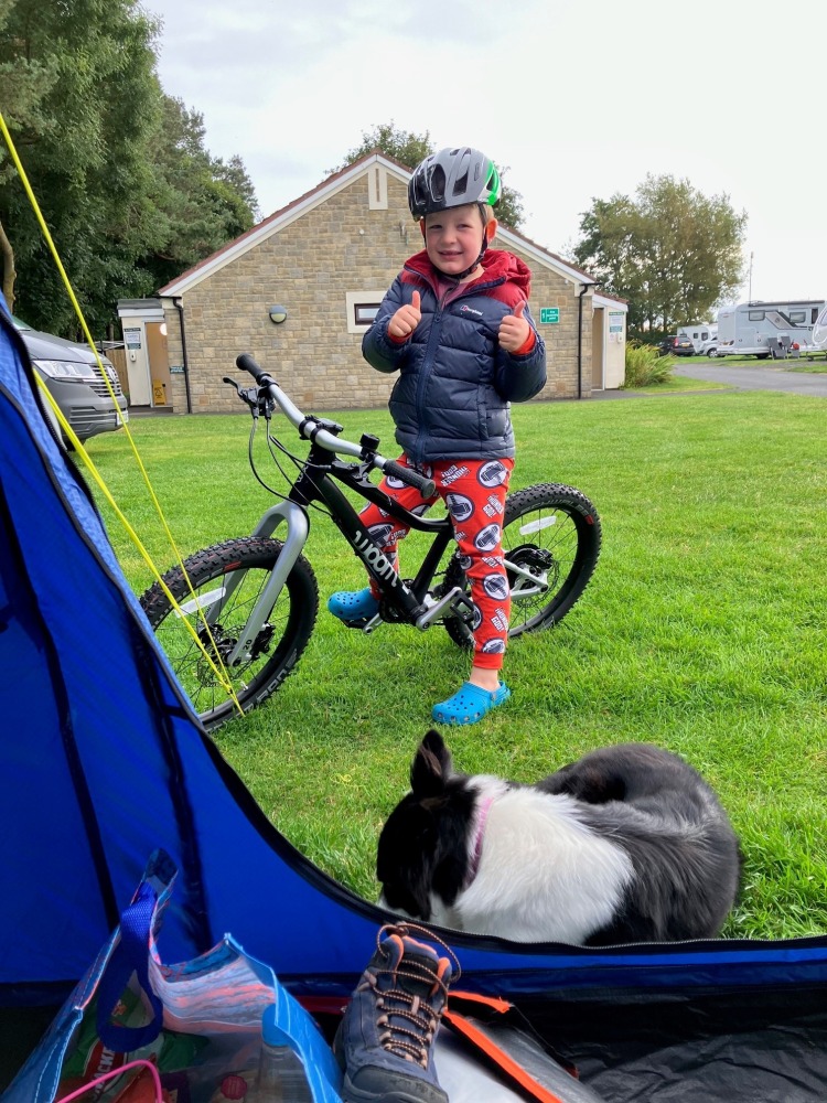 our woom off 4 reviewer Zack riding his bike on a sunny evening at a campsite in his red PJ's