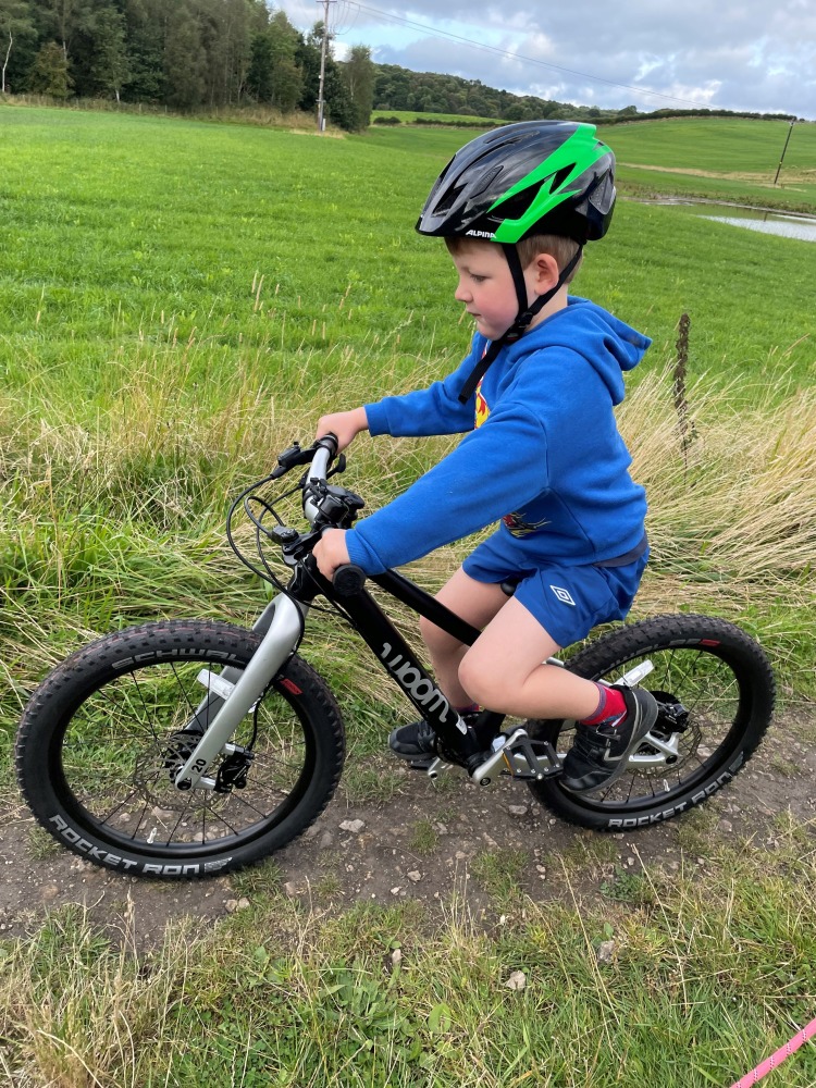 our woom off 4 reviewer Zack riding his bike on a sunny evening on a dirt track