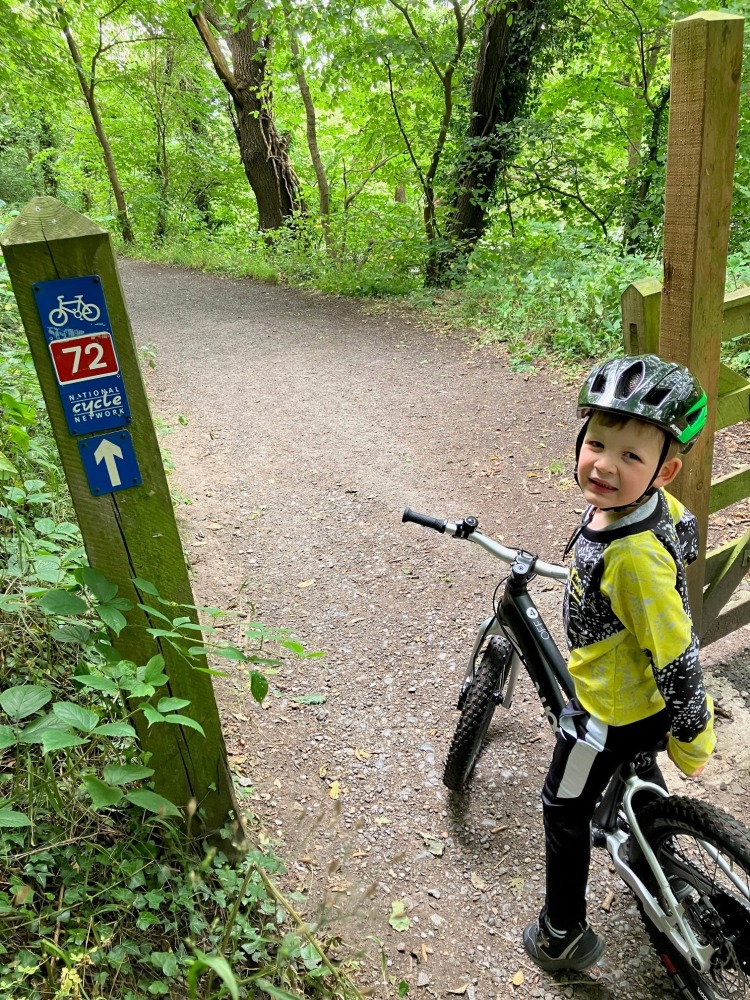 woom OFF 4 review, a photo of Zack, the reviewer in a yellow tshirt riding the black woom off 4 on a narrow trail between trees