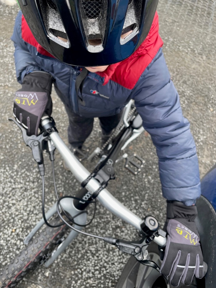 our woom off 4 reviewer Zack riding his bike while wearing a green helmet and a warm blue jacket