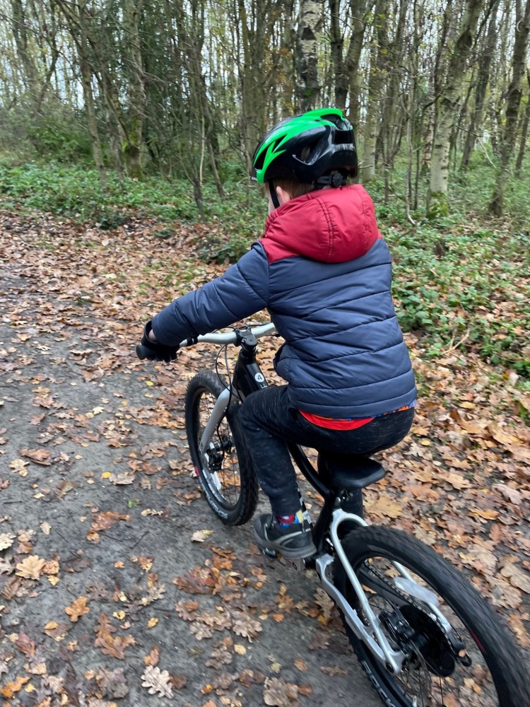 our woom off 4 reviewer Zack riding his bike while wearing a green helmet and a warm blue jacket