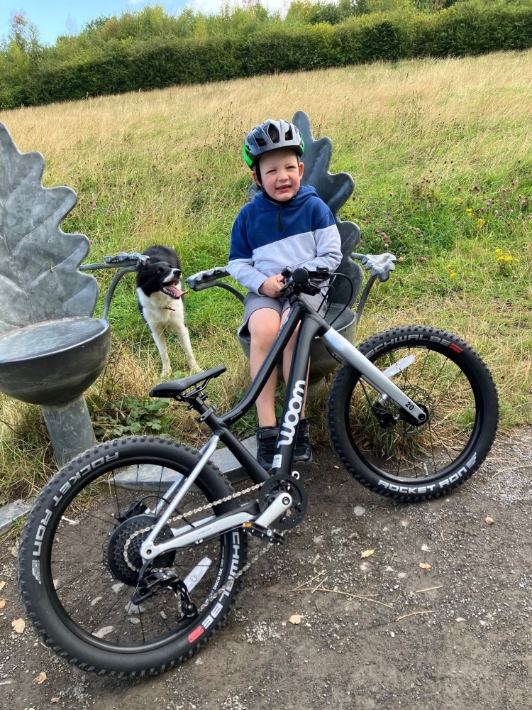 woom OFF 4 review, a photo of Zack, the reviewer in a hoodie having a sit down on a bench mid ride with is black woom 4 mtb