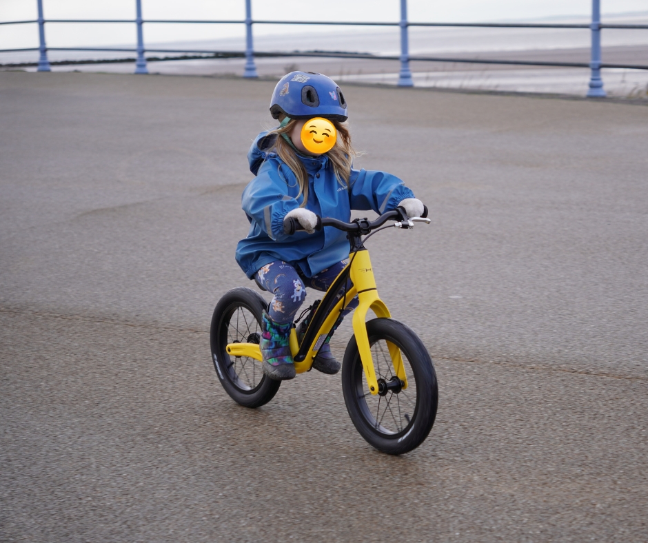 Yellow Hornit AIRO 14 being ridden by a girl in a blue jacket on a sea side prom