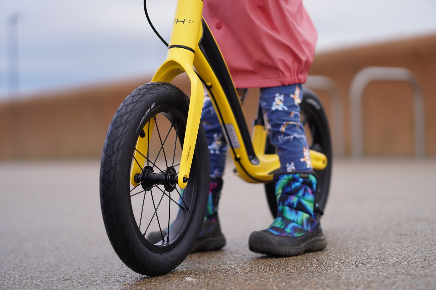 Yellow Hornit AIRO 14 being ridden by a girl in a pink jacket on a large step