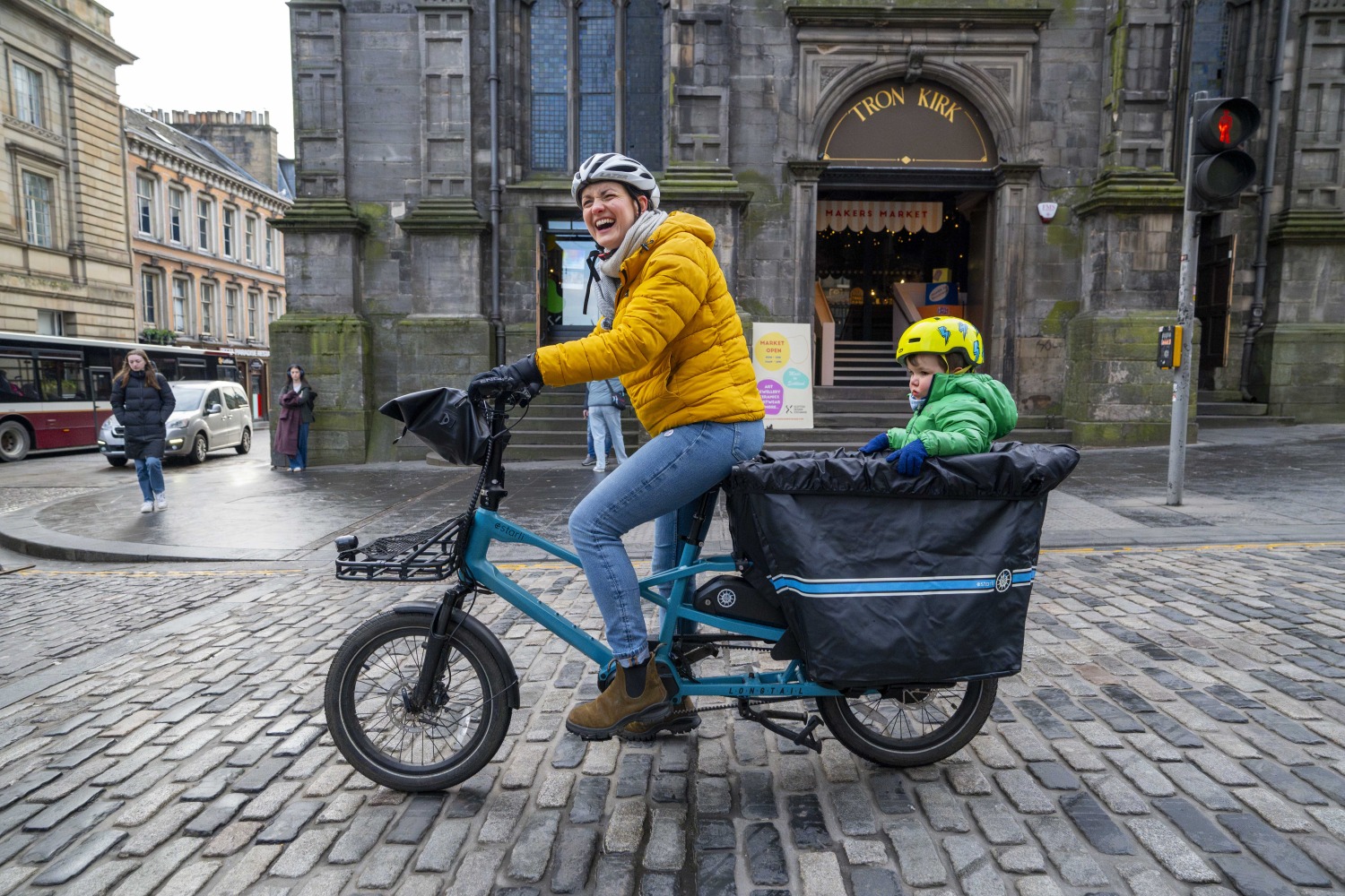 Nia with her son on a blue Estarli ecargo on cobbled stones