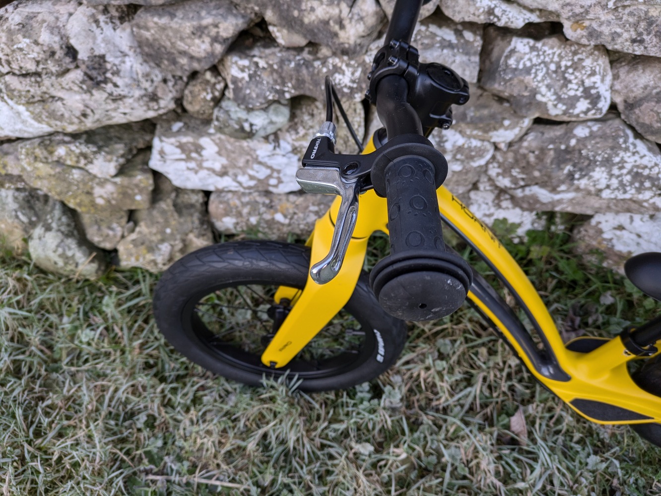 Hornit AIRO 14 review- a close up of the yellow bike against a stone wall - front wheel showing