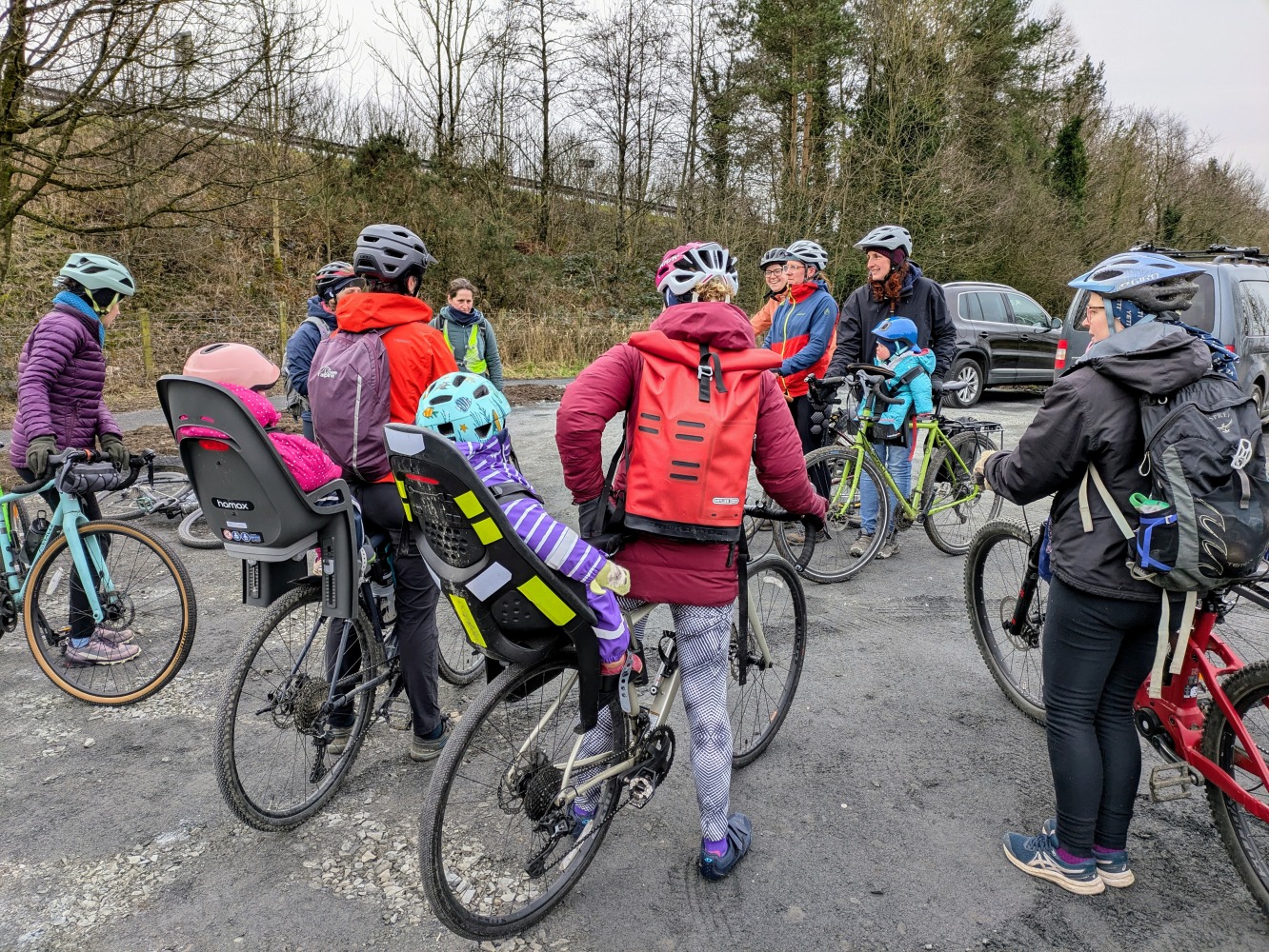 Hamax Zenith Relax Review: a little girl in a pink helmet in her Hamax Zenith Relax rear seat on a family bike ride with lots of other mums and children