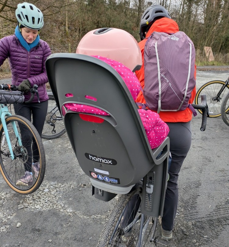 a little girl in a pink helmet in her Hamax Zenith Relax rear seat on her mums bike