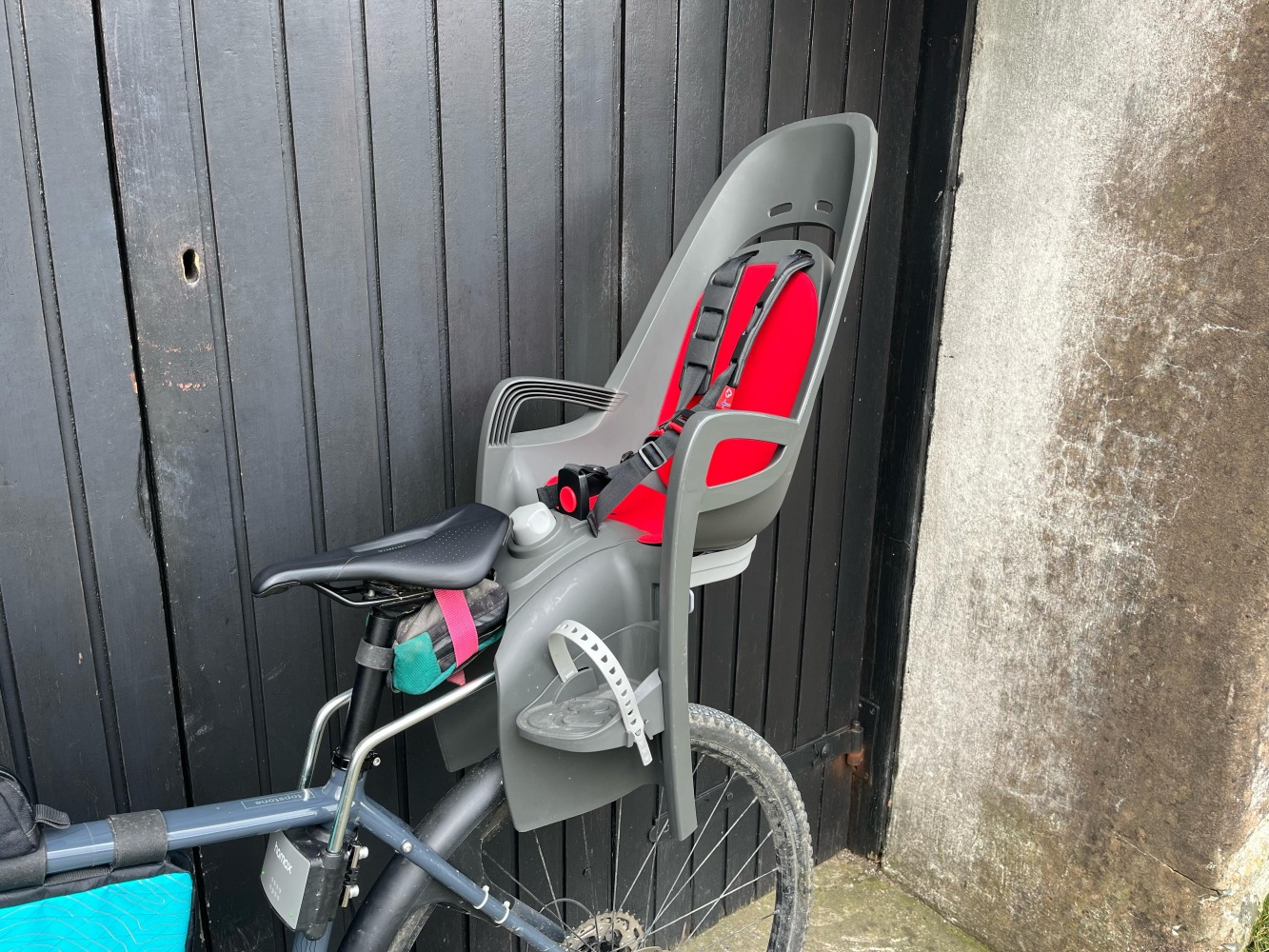 Hamax Zenith Relax Review: grey and red Hamax seat photographed side on by a garage door